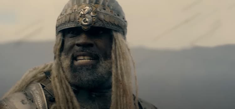 Close-up of Corlys Velaryon in battle armor, grimacing, in daylight with an unclear background.