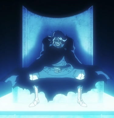 A blue-lit image of a man in a large chair against a black background. The man has long black hair and a mustache, a white tailored suit, and a black cloak that looks rough around the edges. His face is looking slightly downward with a menacing expression.