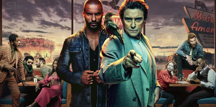 Characters Shadow Moon and Mr. Wednesday stand in front of a background of other characters from the TV show American Gods sitting around tables at a diner.