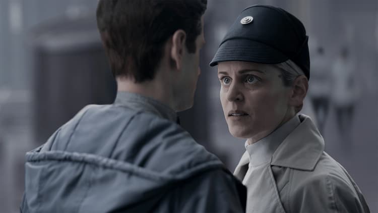 Dedra Meero stands outside on a busy city walkway in the daytime with a look of annoyance and disgust at Syril Karn.