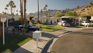 Older houses and older cars align the driveways right next to each other in a picturesque setting.