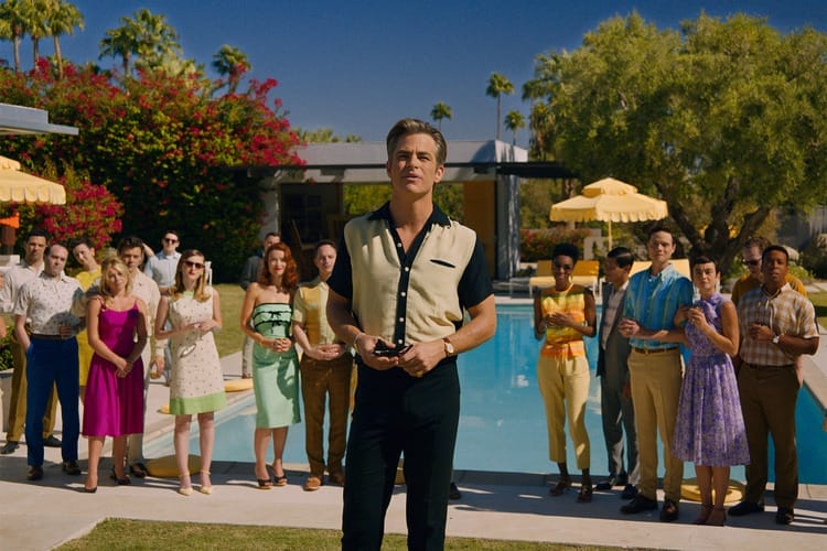 Frank stands in front of a crowd of people who are looking at him in adoration.