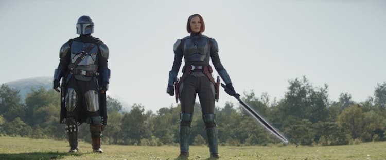 Bo-Katan holds the darksaber while Din Djarin stands at her side