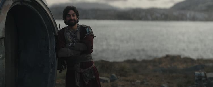 Ezra Bridger leans on a hut with a lake in the background