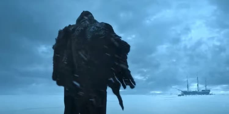 The Creature is standing in the middle of the snow fields. He is wearing a heavy fur coat. A ship is stuck in the ice in the distance. The Creature is looking at the ship. Clouds cover the sky.