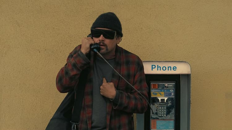 Bob is on the phone with someone in the middle of the day. He is holding the phone up to his right ear with his right hand. He is pointing to his chest in frustration. He is wearing sunglasses that obscure his face.