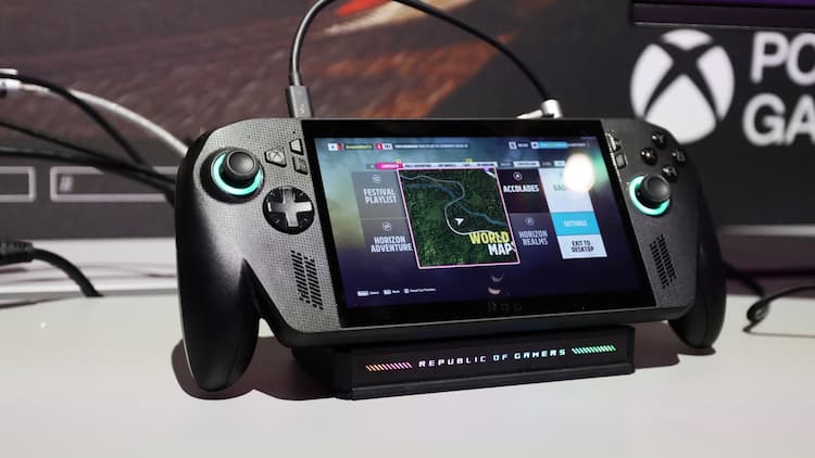 A ROG Xbox Ally X at an event. It is on a Republic of Gamers stand with a cord connected to the top. Xbox branding is in the background.