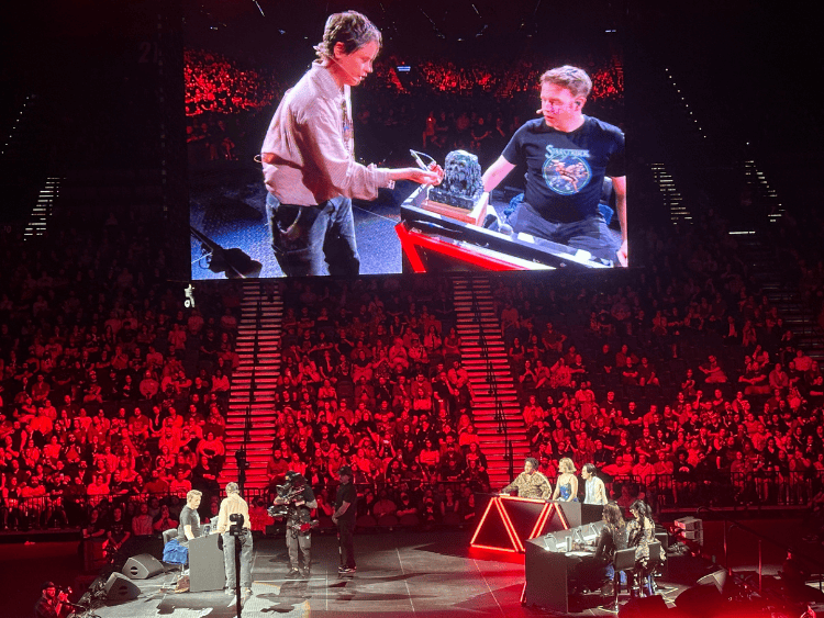 Ally approaches Brennan to roll in the box of doom. The arena is lit red for drama.