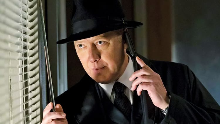Raymond Reddington is looking through some window blinds. He is holding a phone to his left ear.