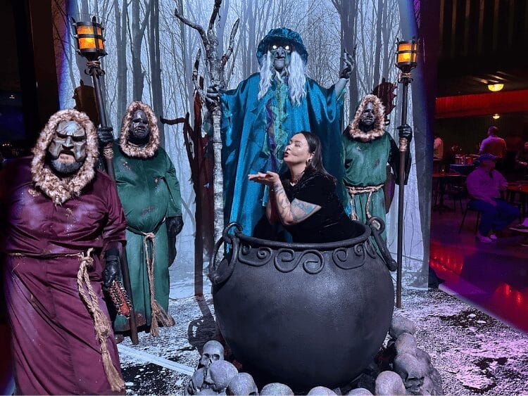 Icelandic folklore monster Grýla is a large monster wearing a robe and holding a staff. He's flanked by three men in robes and masks, and they are in front of a snowy backdrop. There is a large cauldron in front of them, and the cauldron contains the author. She's making a dumb face and is blissfully unaware of the passing of time. She should be working, but instead she's pretending this is more productive instead. 