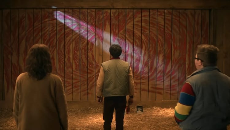 From left to right, Joyce, Will and Derek are looking at a barn door with a picture on it.