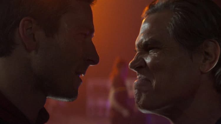 Ben Richards is face-to-face with Dan Killian. Ben has a serious look on his face. Dan is scrunching up his face while looking at Ben. Various production staff are walking by in the background.