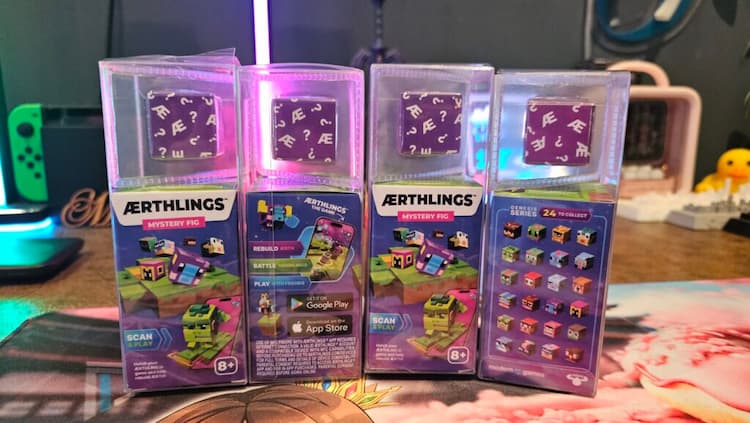 Four Aerthling mystery boxes. The four boxes are lined up on a desk. The Aerthlings are wrapped up inside paper and plastic.