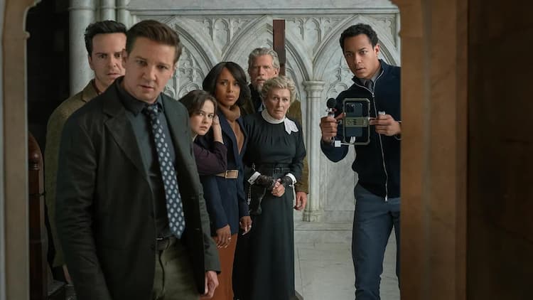 The members of Wicks's church are looking inside a hidden room in the church. They are all looking into the room with concern. A man on the right is filming with his phone in a stabiliser. The white church walls are in the background.