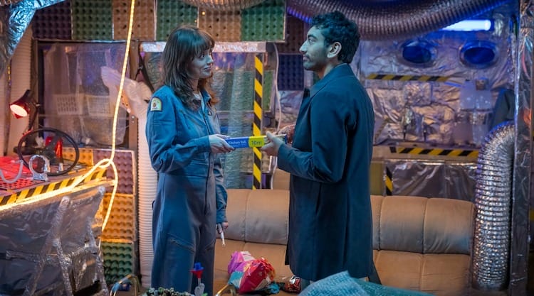 Evie, left, is giving a roll of foil to Noa, right. The room looks like a DIY spaceship interior.