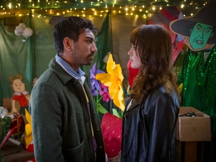 Noa, left, and Evie, right, are looking at each other intensely. There are props from The Wizard of Oz in the background.