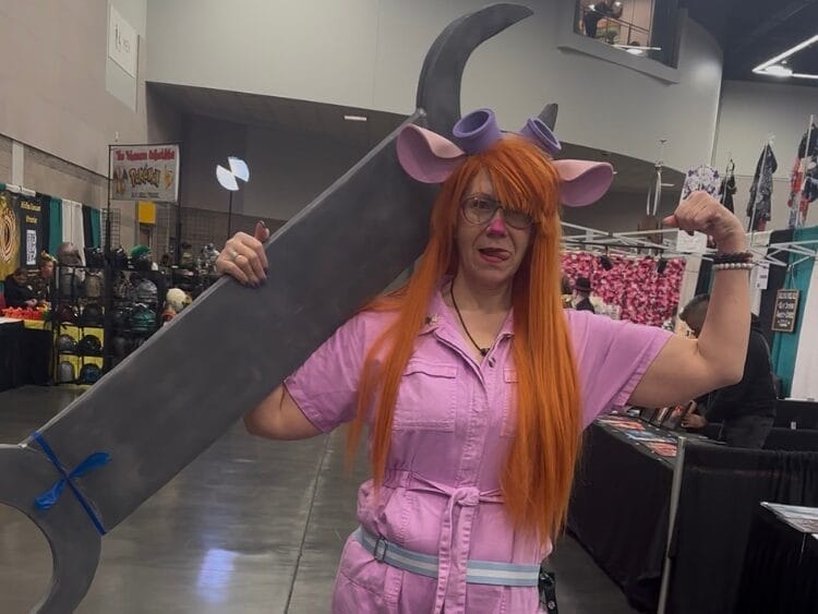 Cosplayer dressed as Gadget Hackwrench. They are in a pink jumpsuit with a massive wrench.