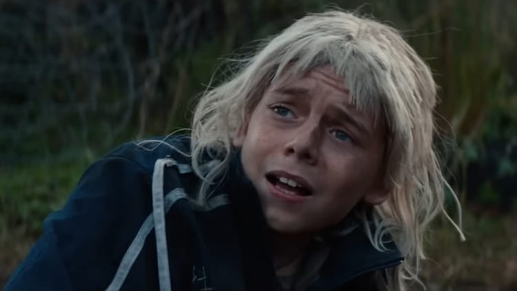 Spike is lying on the floor. He is wearing a blonde wig. He looks scared.